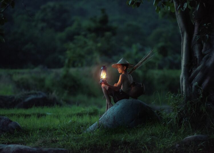 Un ragazzo accende una lanterna in una campagna del Vietnam