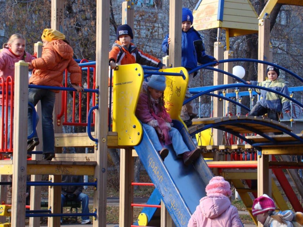 Bambini che giocano sugli scivoli di un parco giochi, in inverno