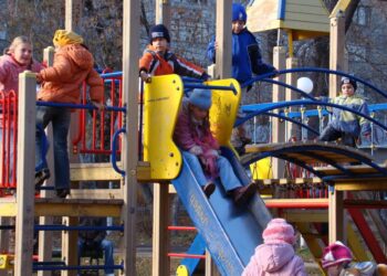 Bambini che giocano sugli scivoli di un parco giochi, in inverno