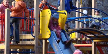 Bambini che giocano sugli scivoli di un parco giochi, in inverno