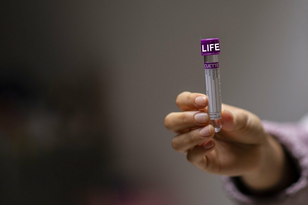 Una mano mostra una provetta di laboratorio con la scritta "life"
