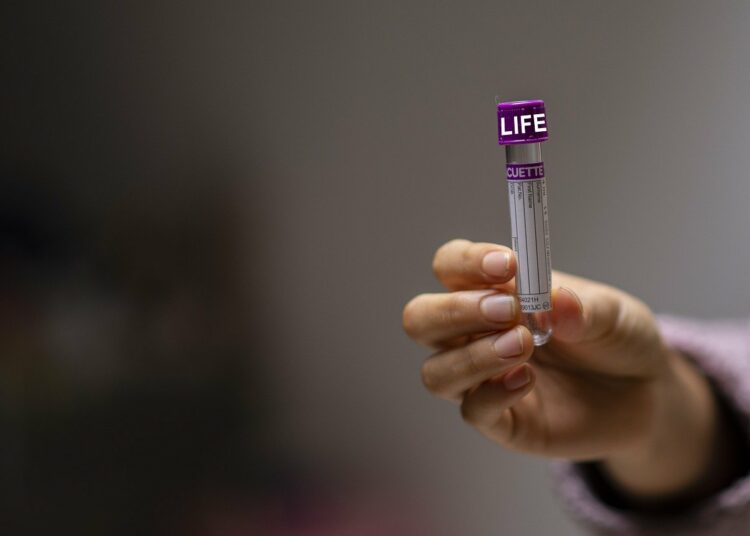 Una mano mostra una provetta di laboratorio con la scritta "life"