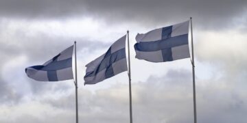 Tre bandiere della Finlandia che sventolano nel cielo nuvoloso