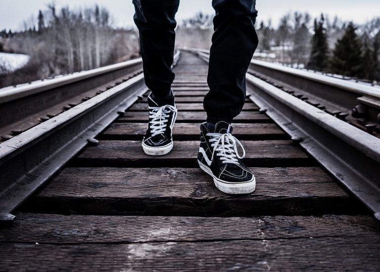 Un ragazzo cammina sulle rotaie