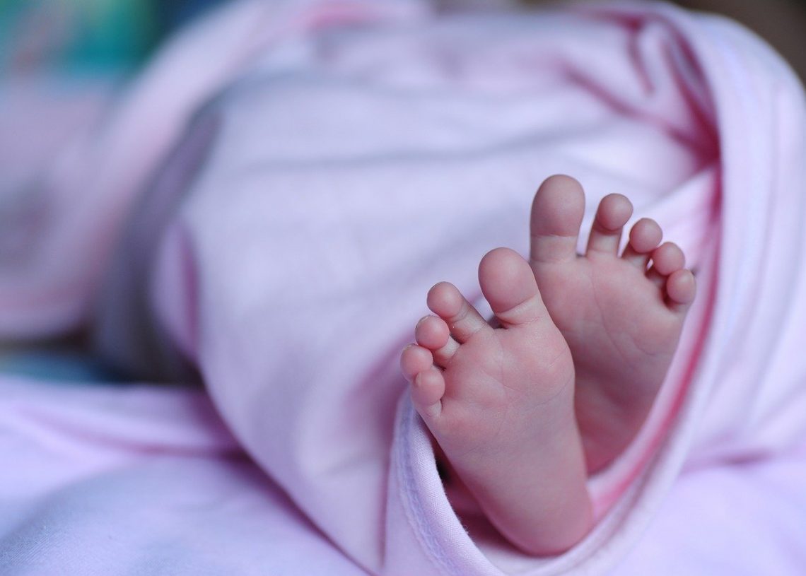 Baby girl's feet wrapped in a pink blanket