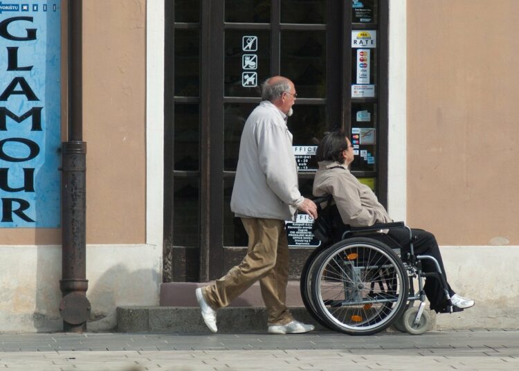 Un familiare spinge una donna in sedia a rotelle