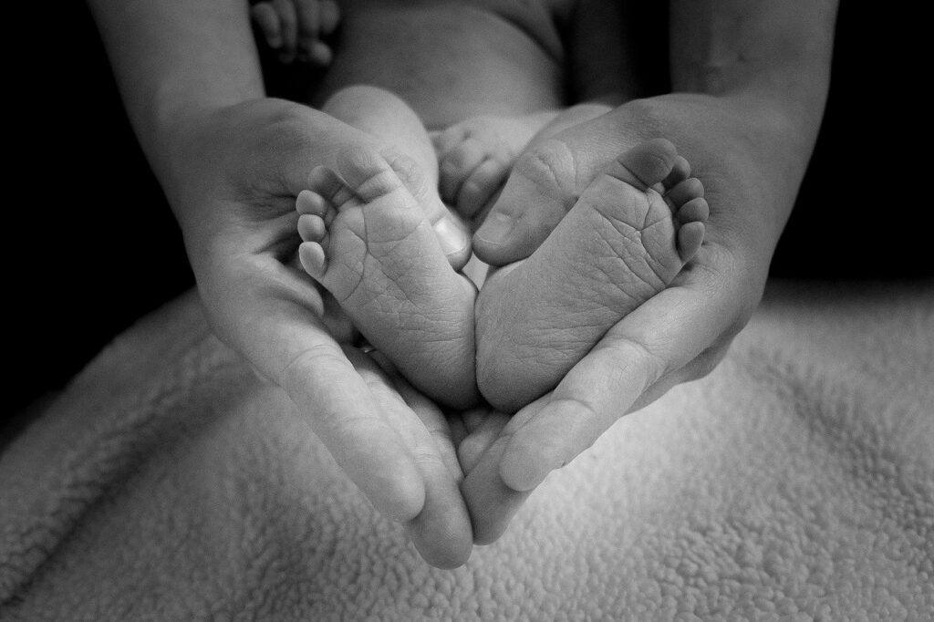 Piedini di un neonato fra le mani