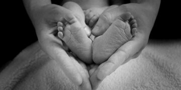 Piedini di un neonato fra le mani