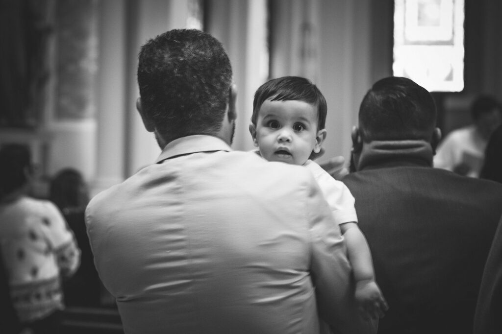 Bambino in braccio del padre durante la Messa