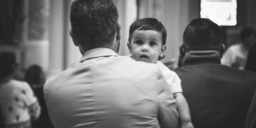 Bambino in braccio del padre durante la Messa