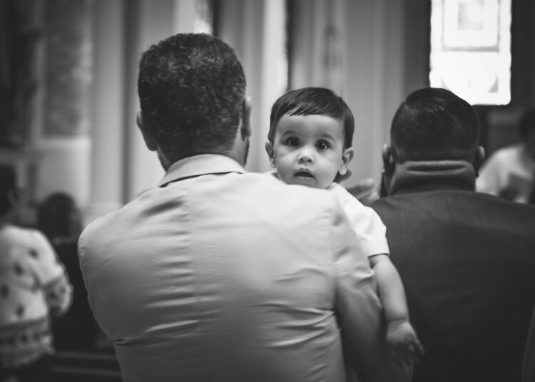 Bambino in braccio del padre durante la Messa