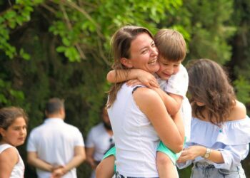 Mamma che ride con figlio in braccio