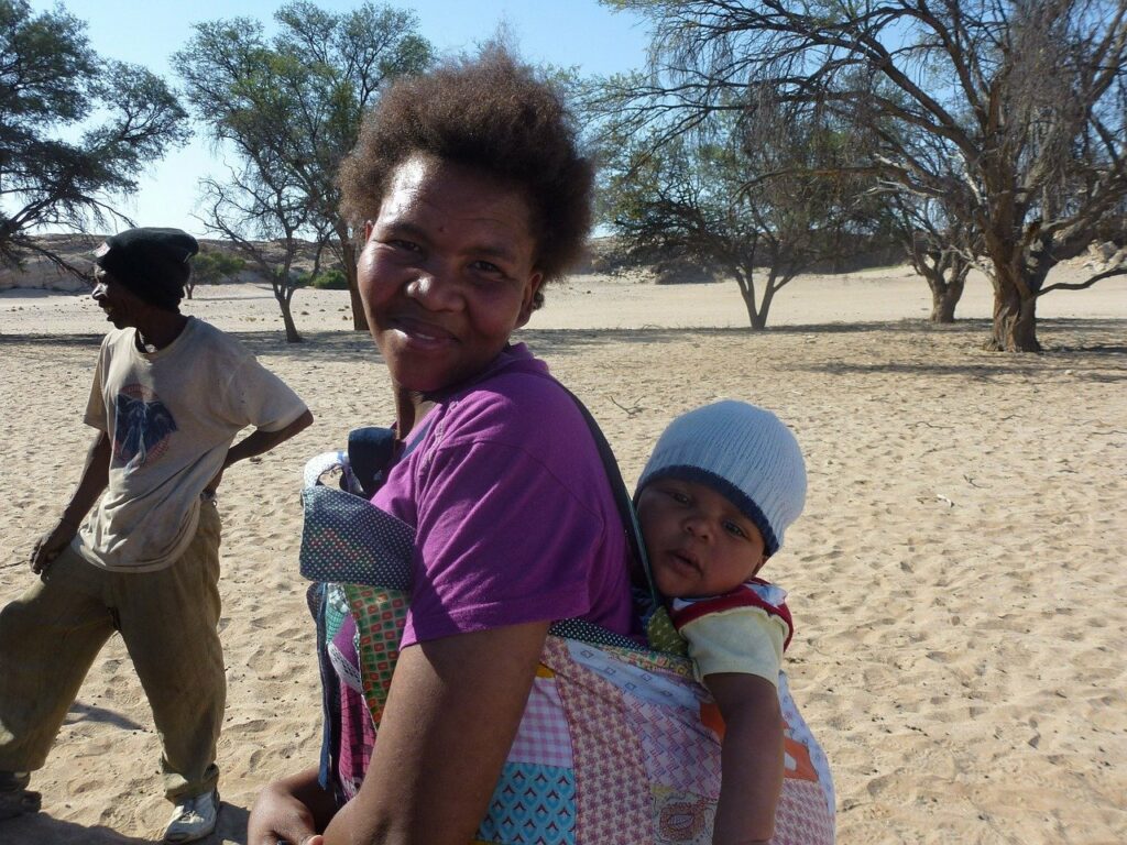 Donna con bambino in fascia sulle spalle, in Namibia